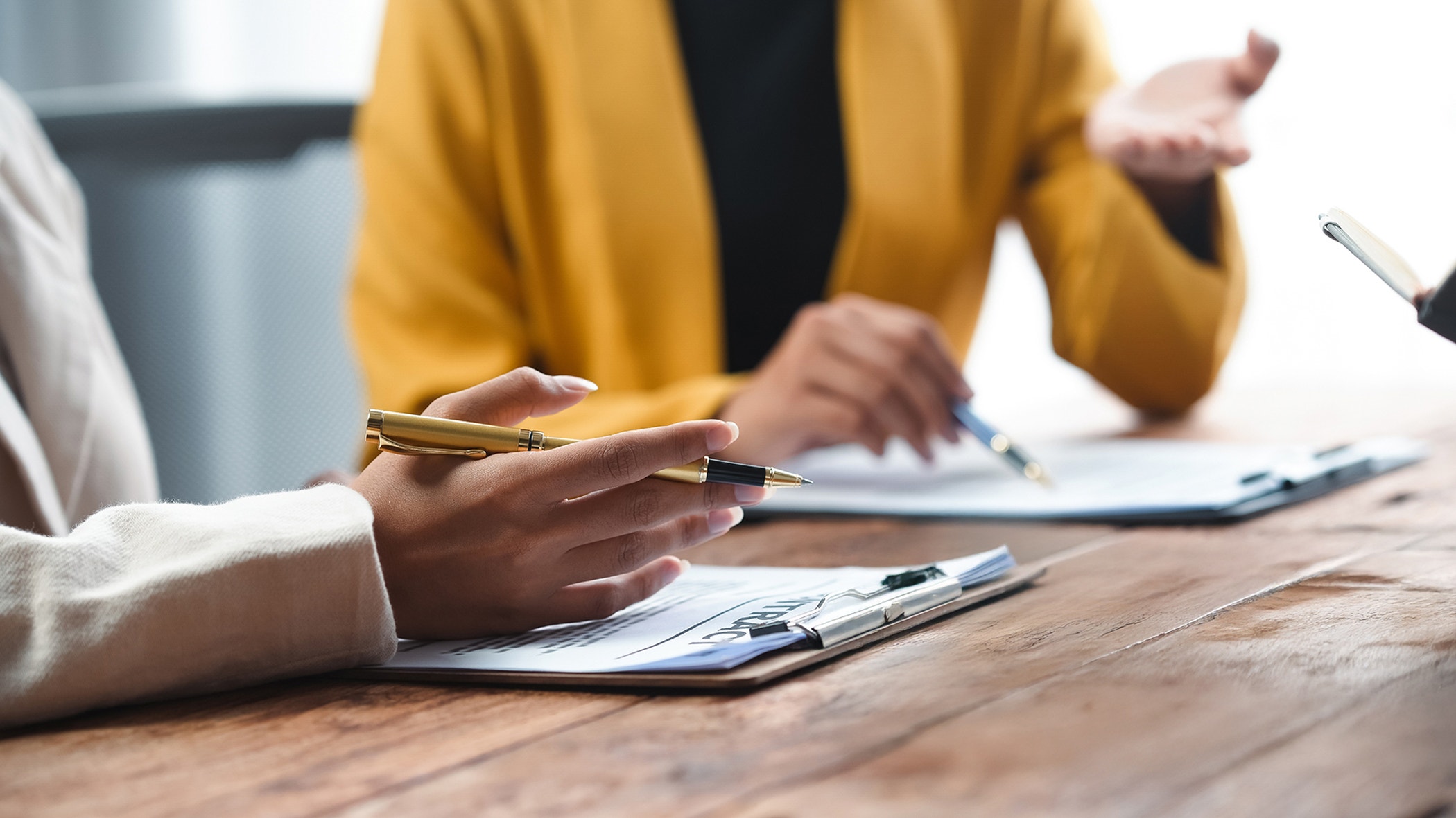 A professional consultation scene featuring hands discussing documents and a gavel, symbolizing legal proceedings and decision-making.