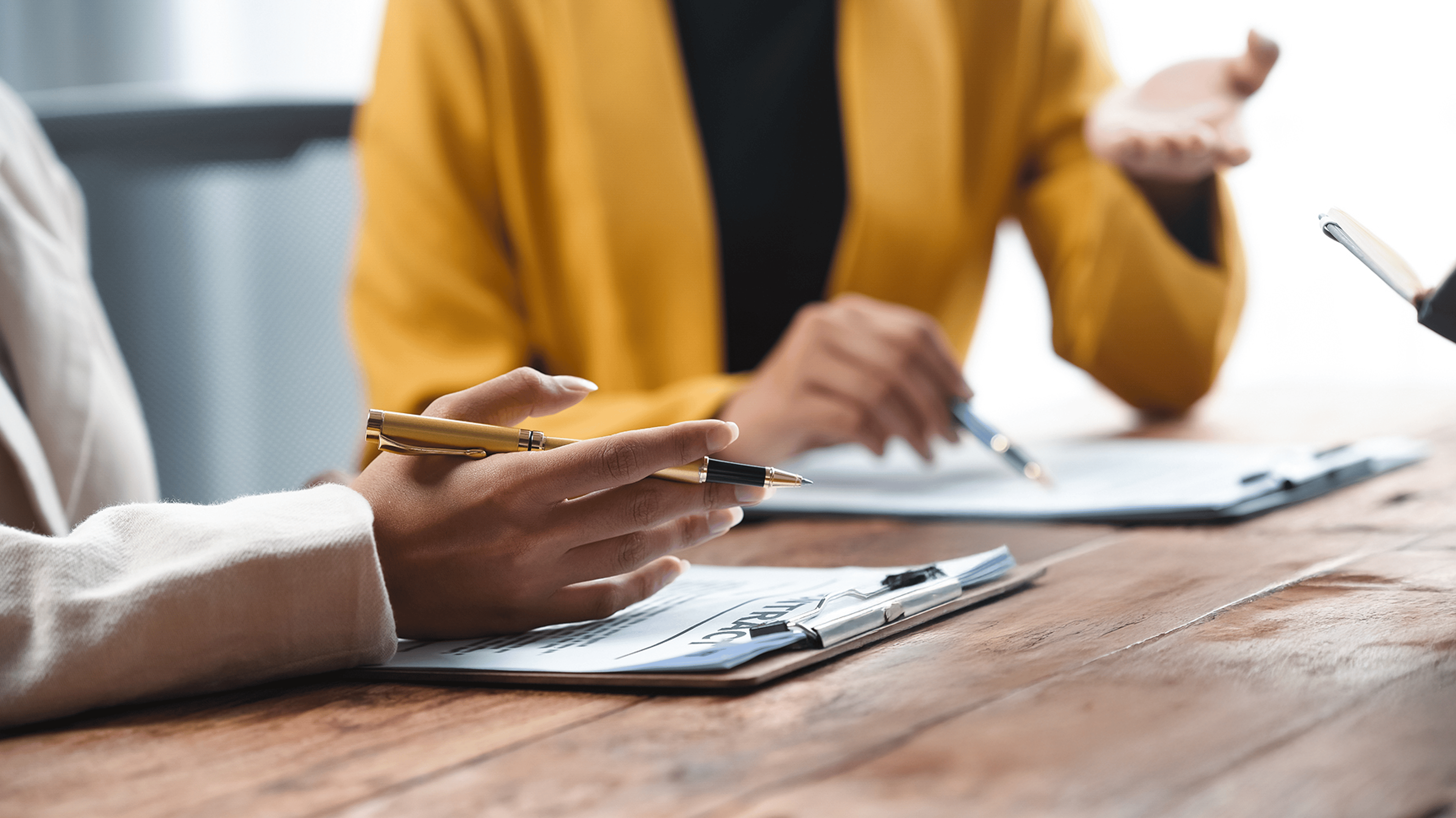 A professional consultation scene featuring hands discussing documents and a gavel, symbolizing legal proceedings and decision-making.