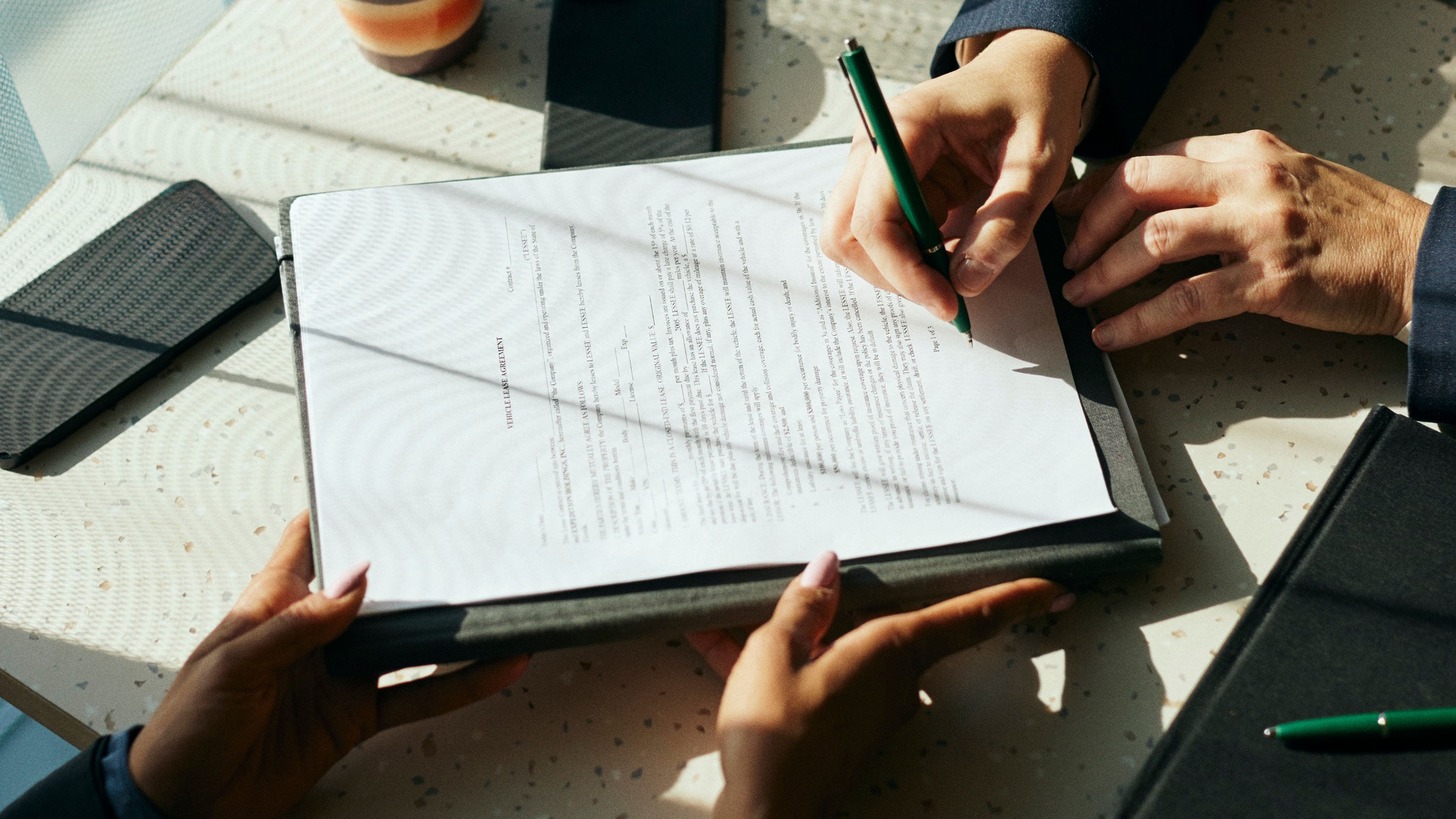 High angle view of female client signing contract with businesswoman in office.