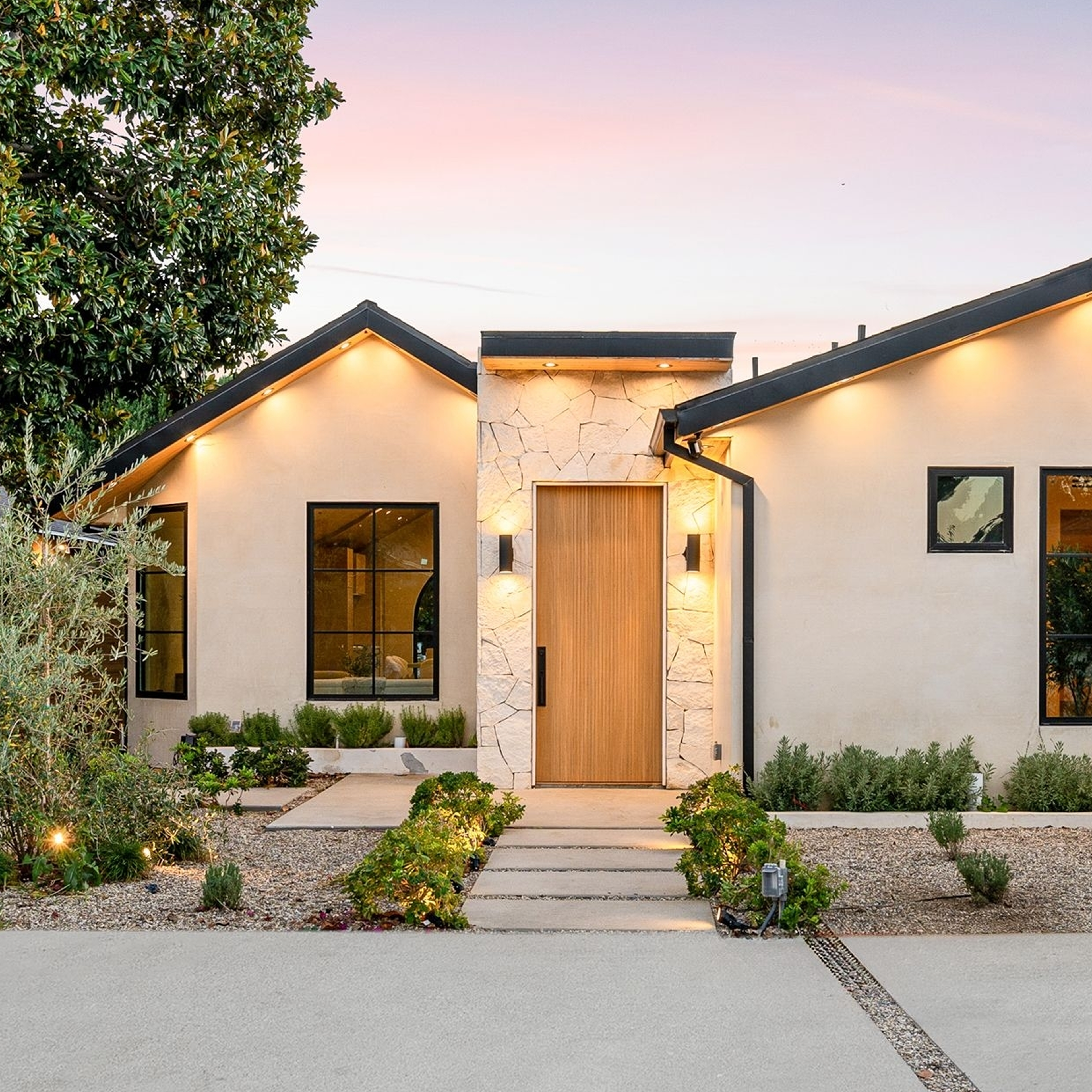 Modern single-story house with a minimalist garden at sunset, featuring clean lines and warm lighting.