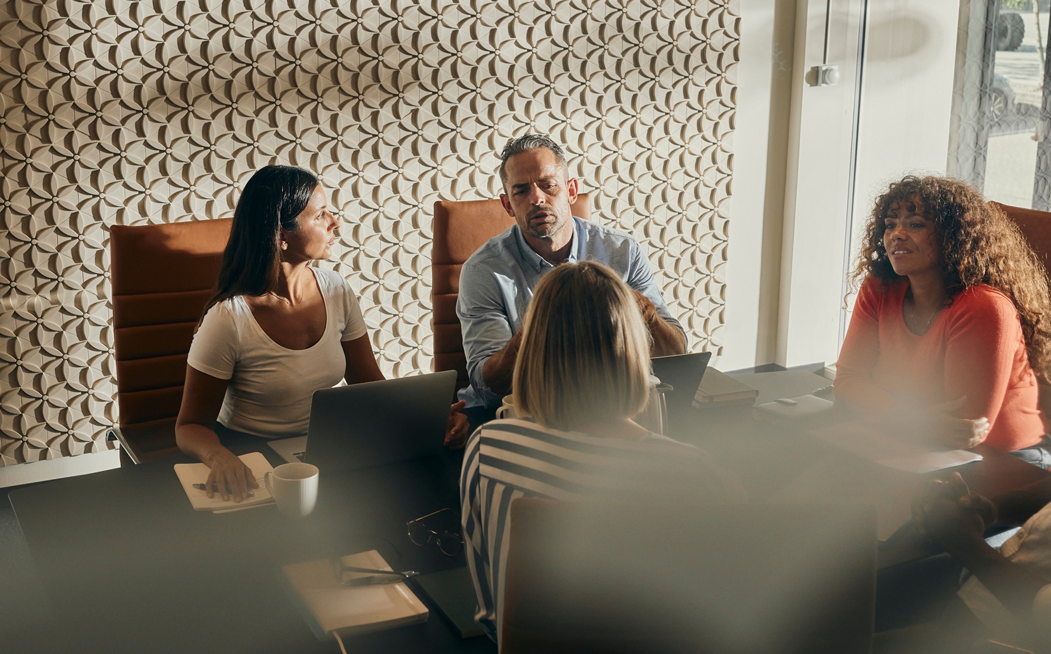 A diverse group of professionals actively participating in a business meeting. They are seated around a table in a modern office setting, emphasizing teamwork, collaboration, and productivity.