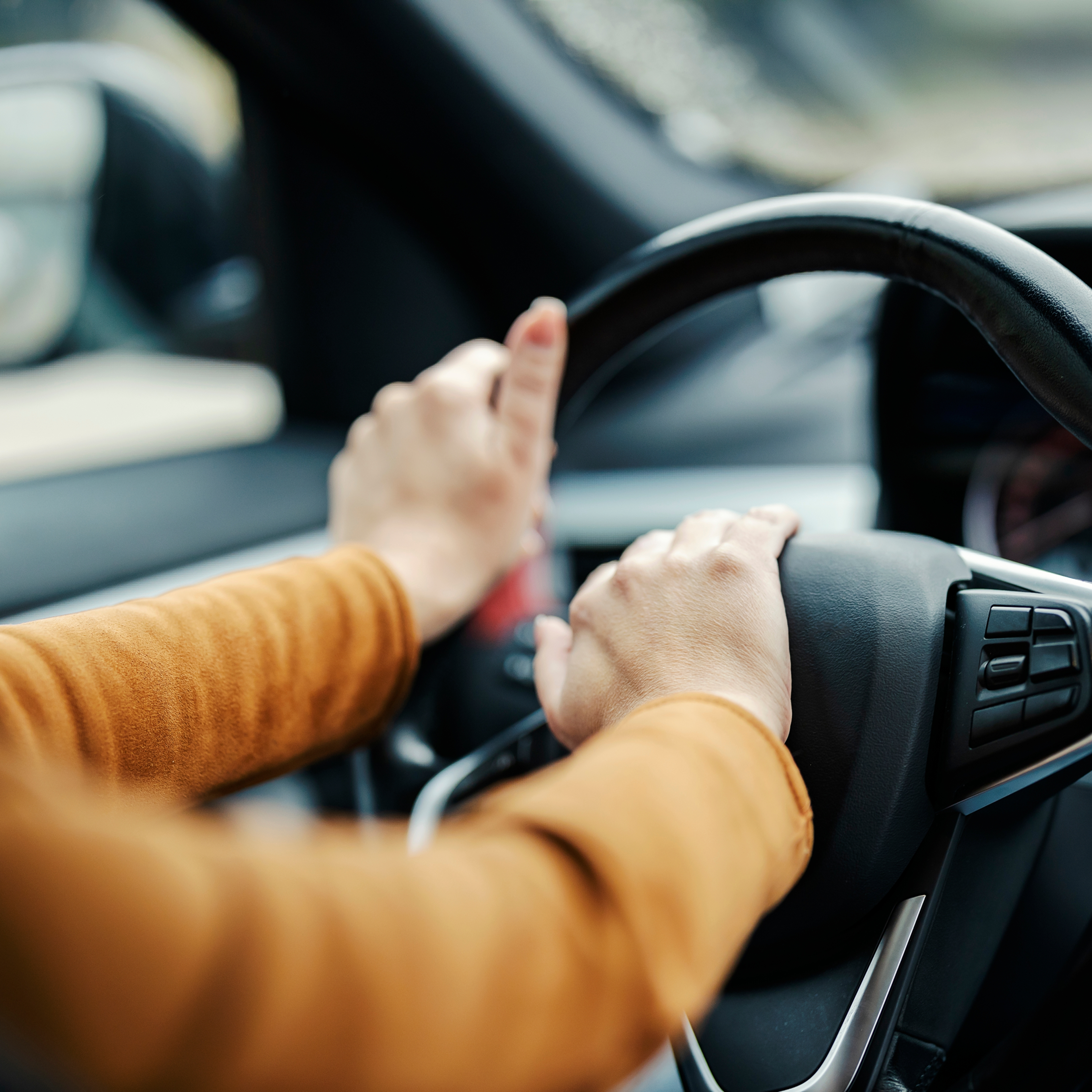Back view of a woman honking at drivers in traffic.