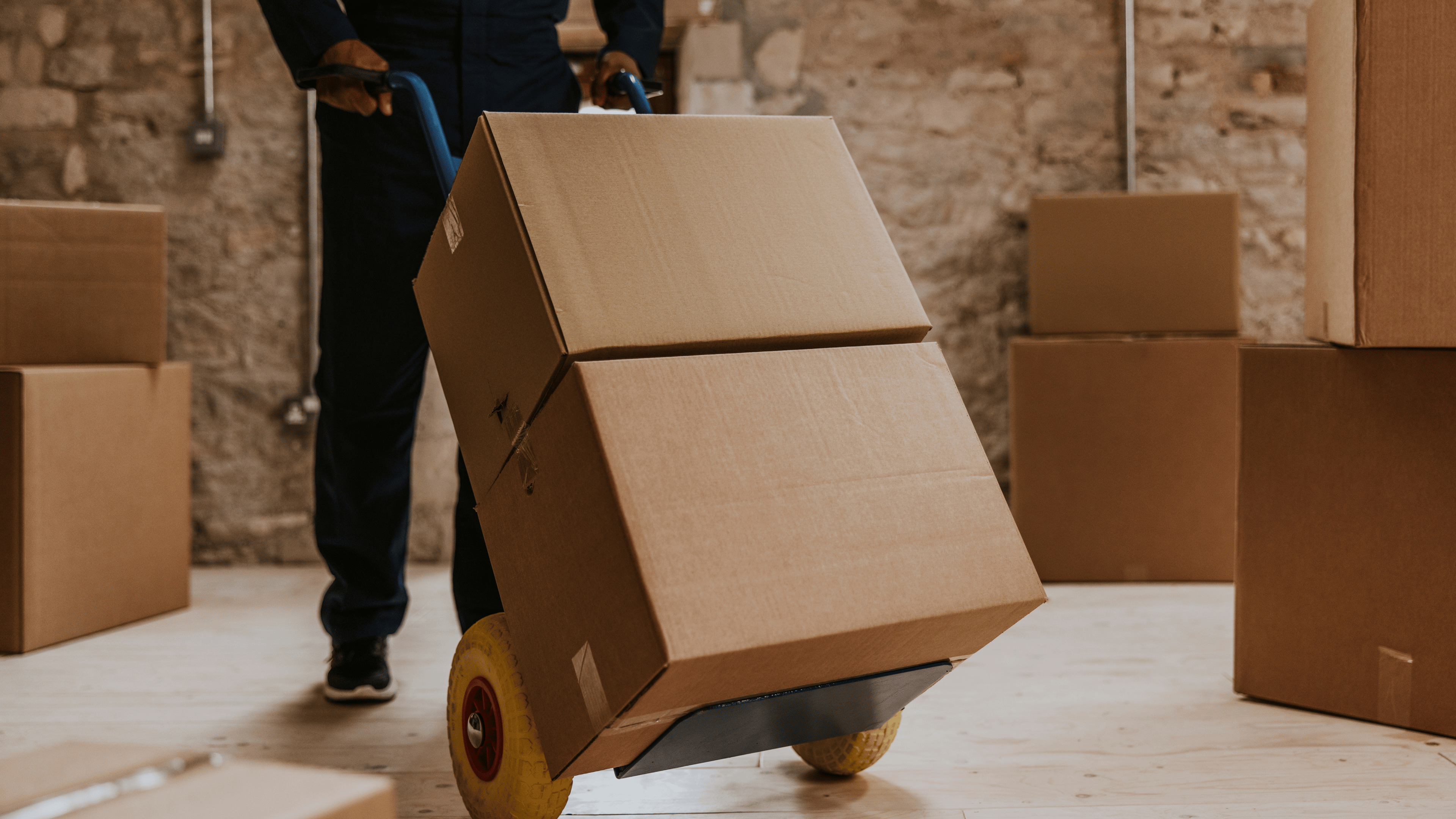 Moving workers unloading boxes into a new home, delivering packages as part of a professional home moving service.
