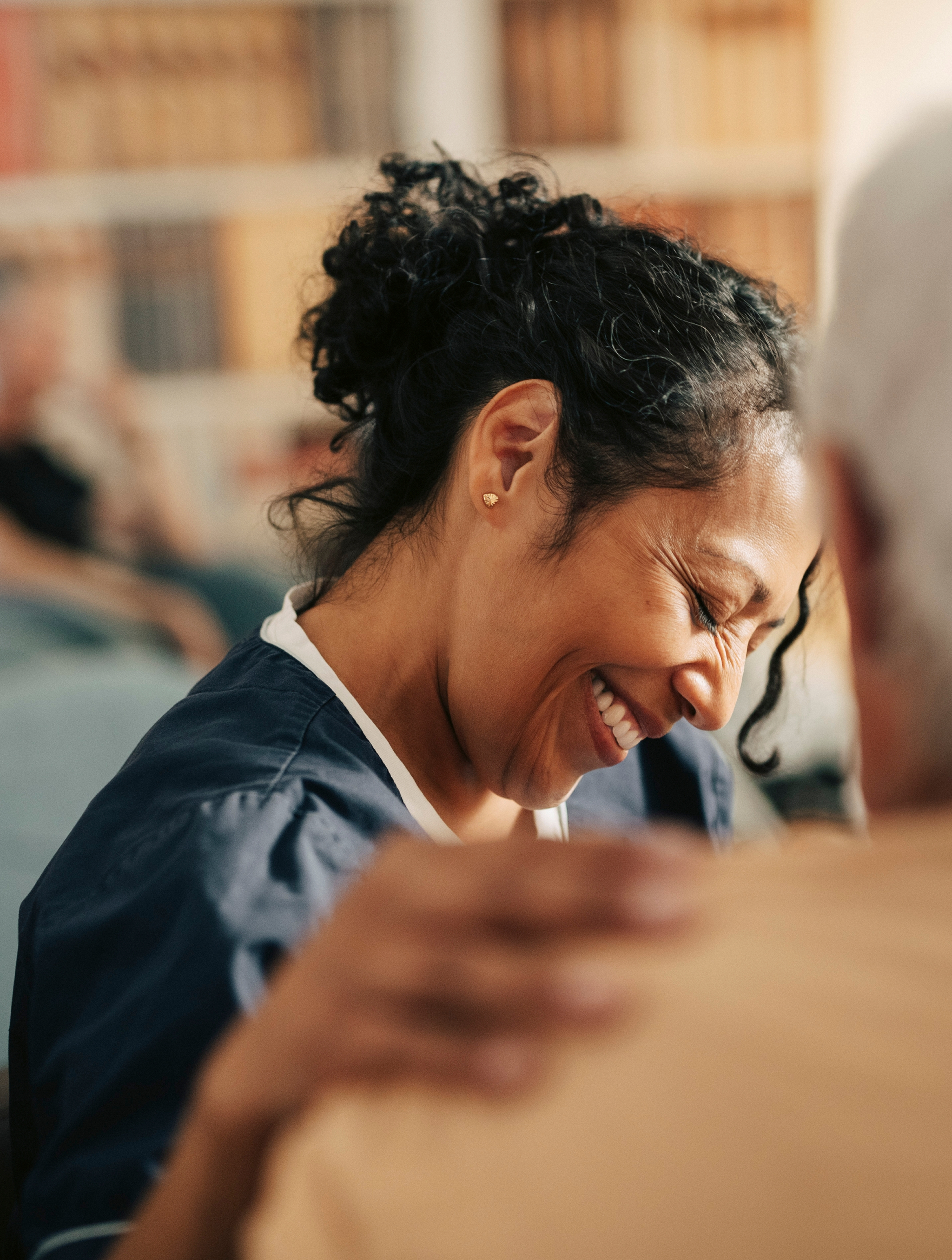 Smiling female nursing assistant with hand on shoulder of senior patient at retirement home.