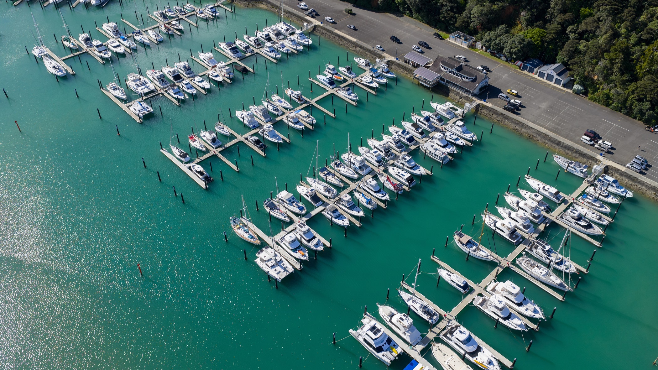 Aerial view of boats resting in the marina's turquoise waters, a stark contrast to the lush green coastline.