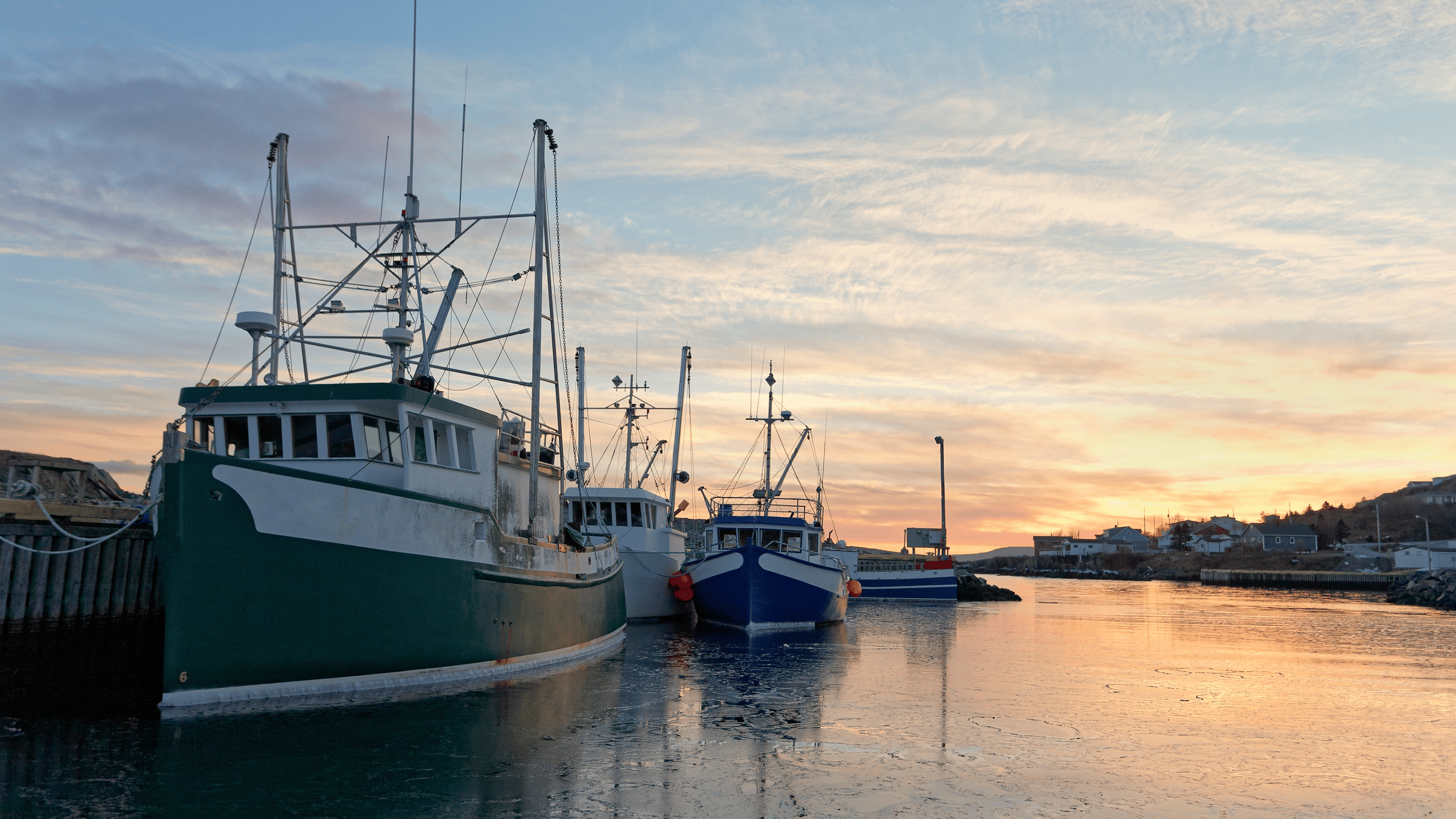 Fishing boats moored at the dock at sunset during the winter.