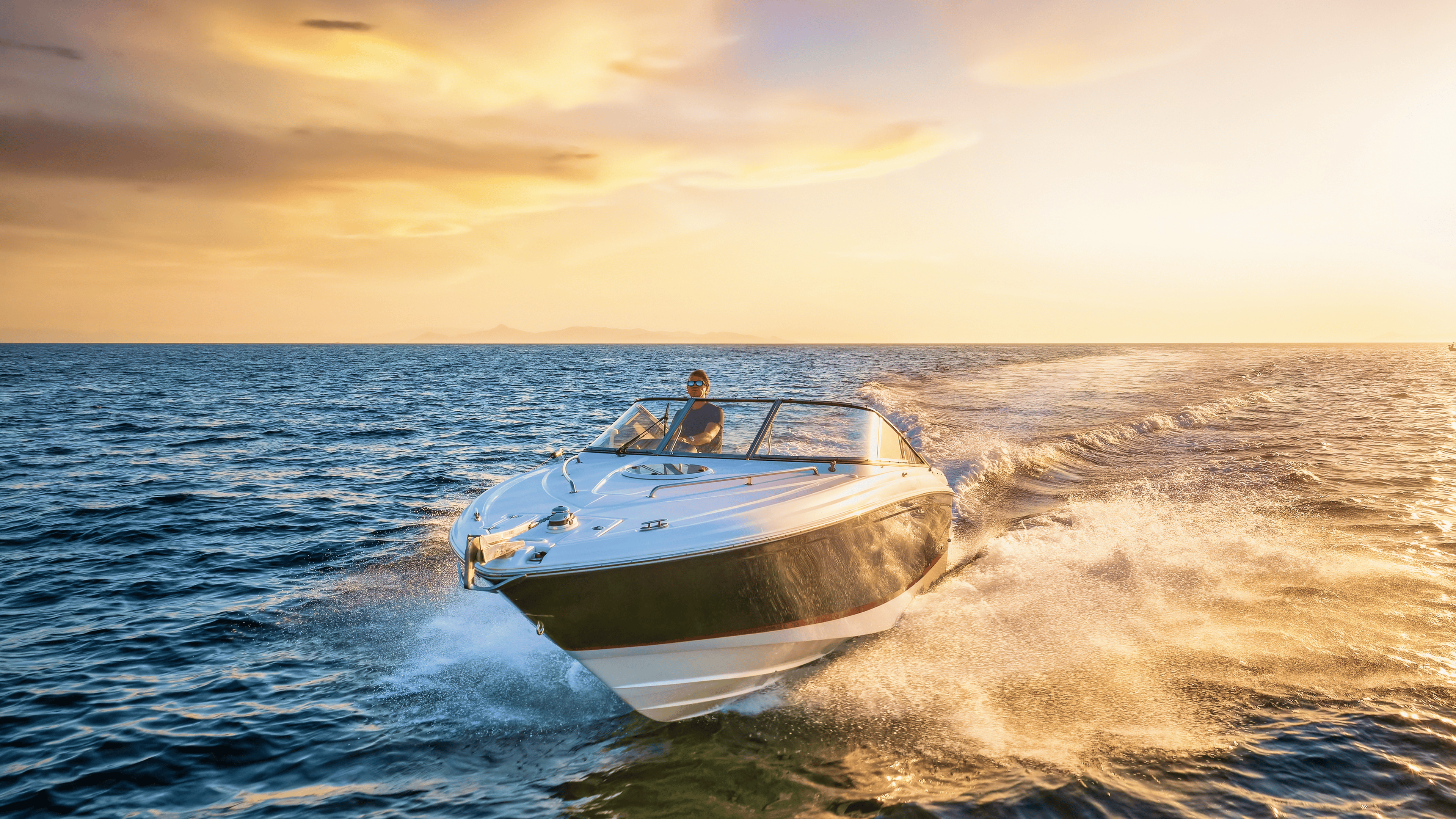 Front view of a sports motor boat cruising with high speed over the blue sea during summer sunset time.