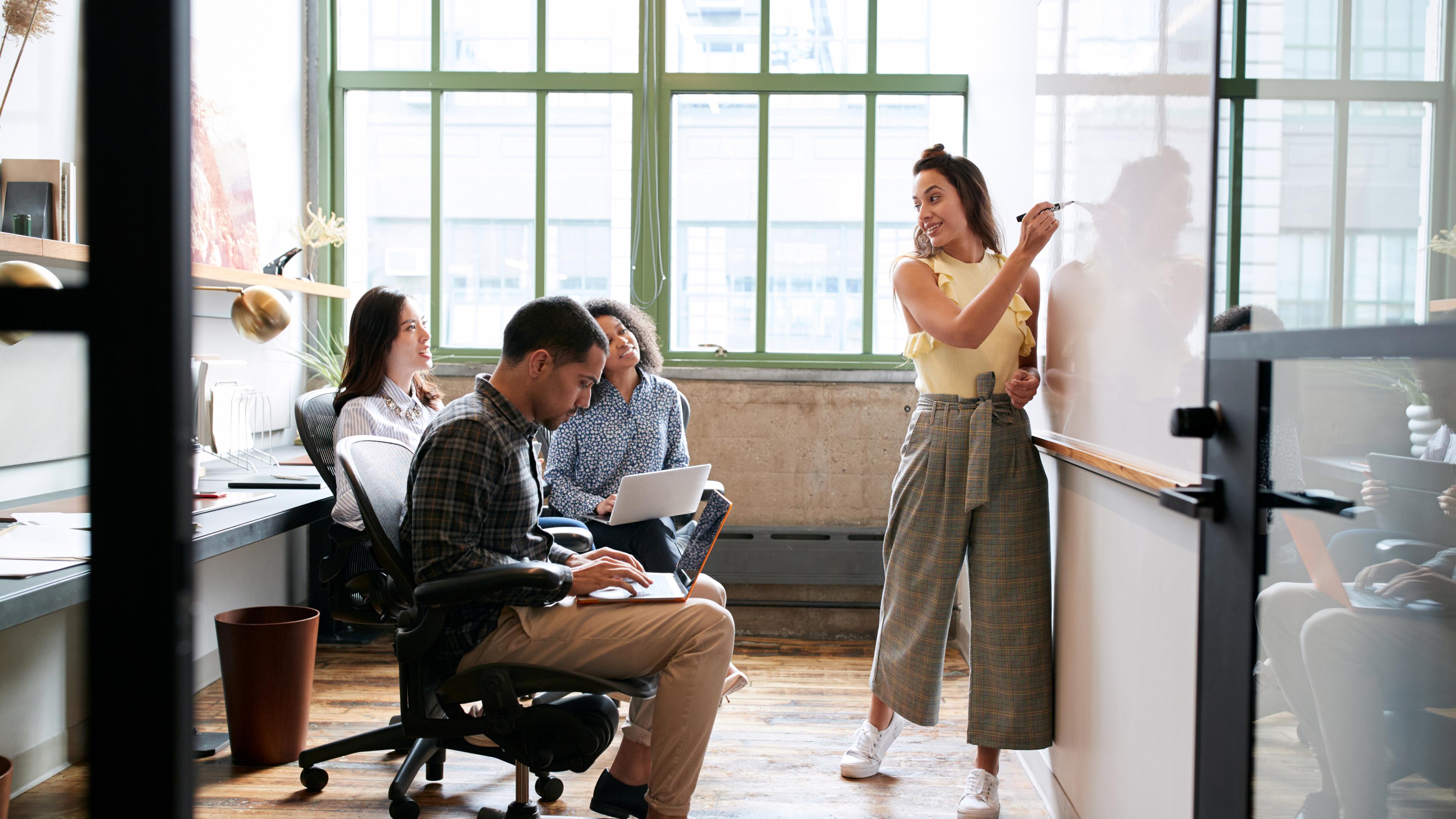 Woman using whiteboard in a small team meeting.