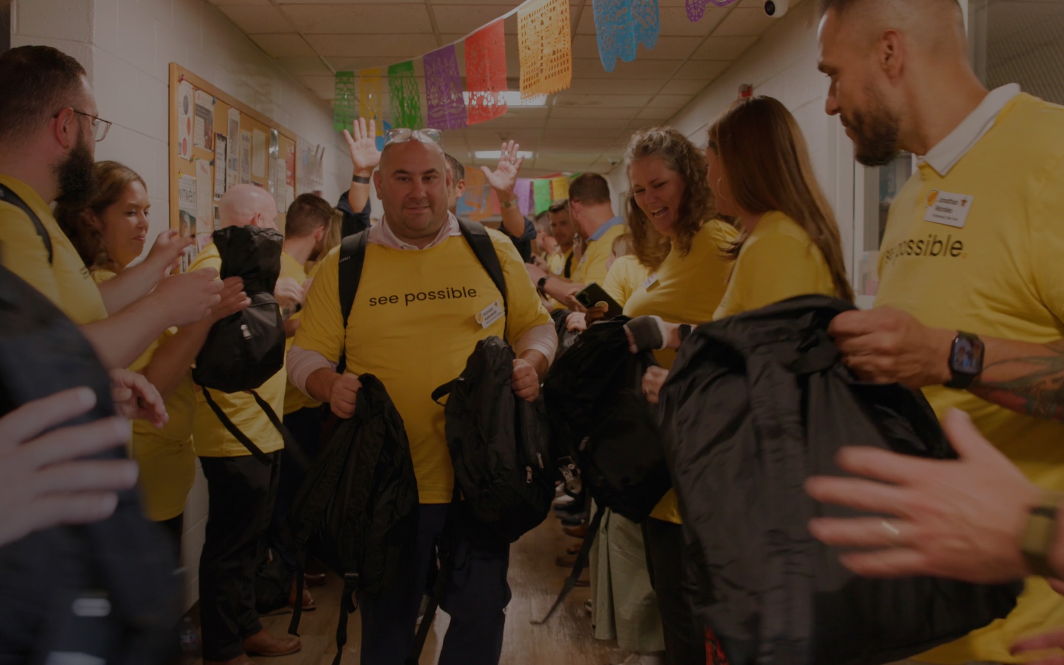 Speaker presenting on stage at a conference with a large yellow screen displaying the phrase “see possible.”