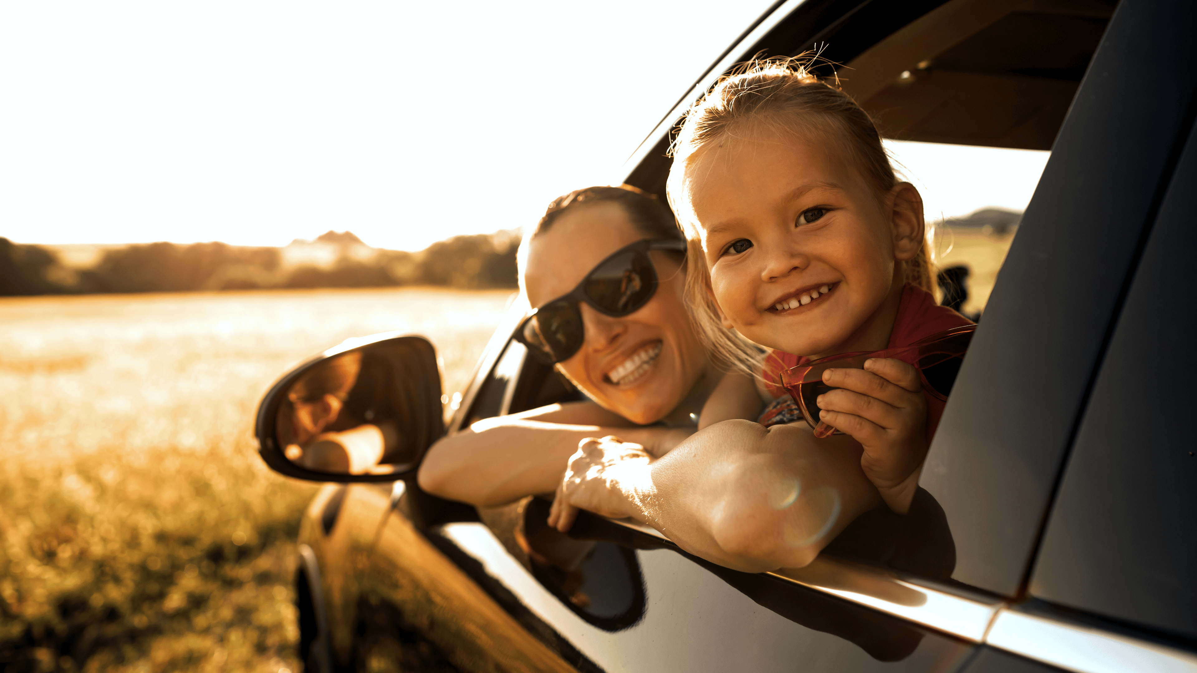 Portrait of happy mother and child in car smiling enjoying summer family holiday road trip