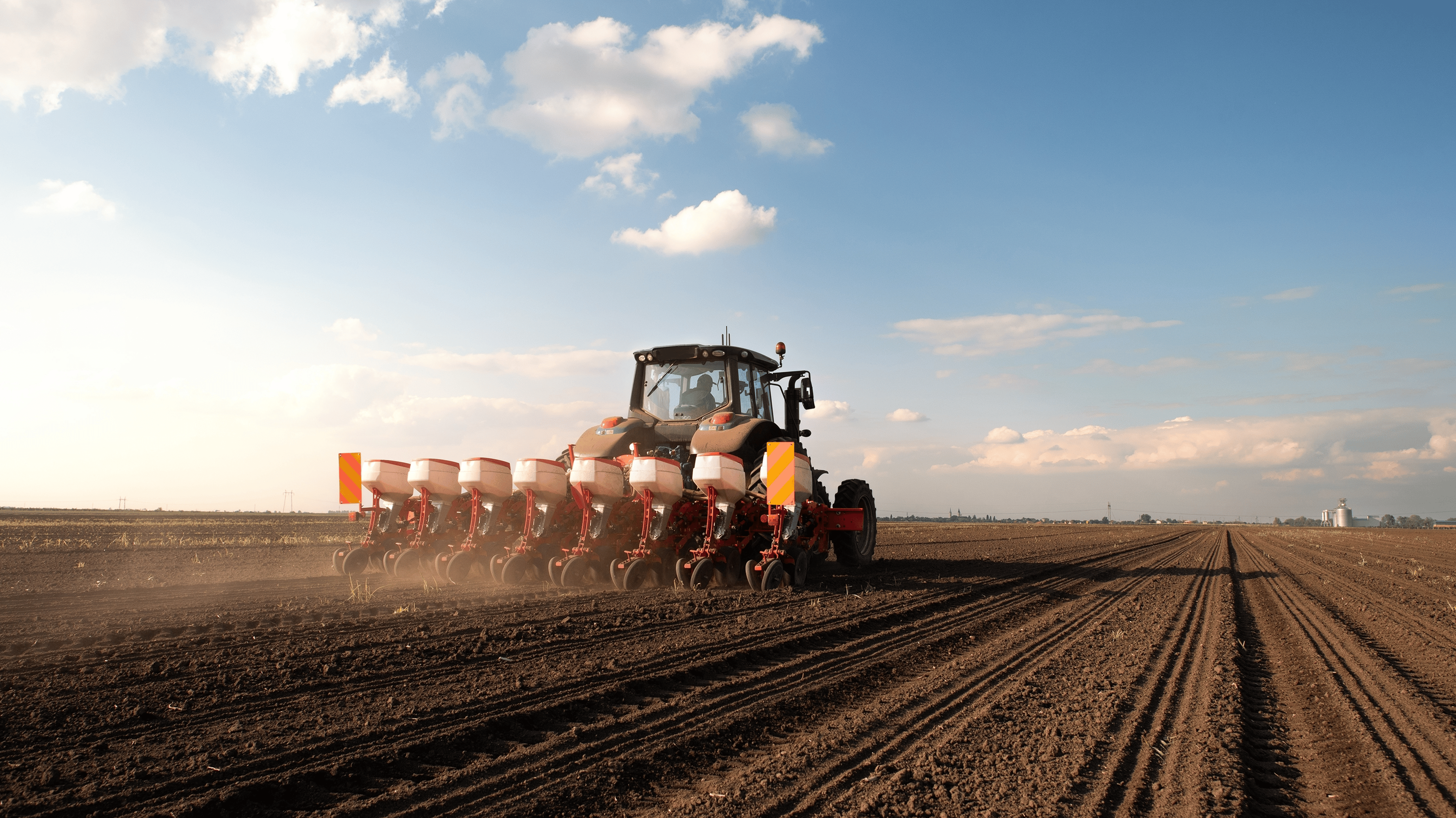 Farmer with tractor seeding - sowing crops at agricultural field. Plants, wheat.