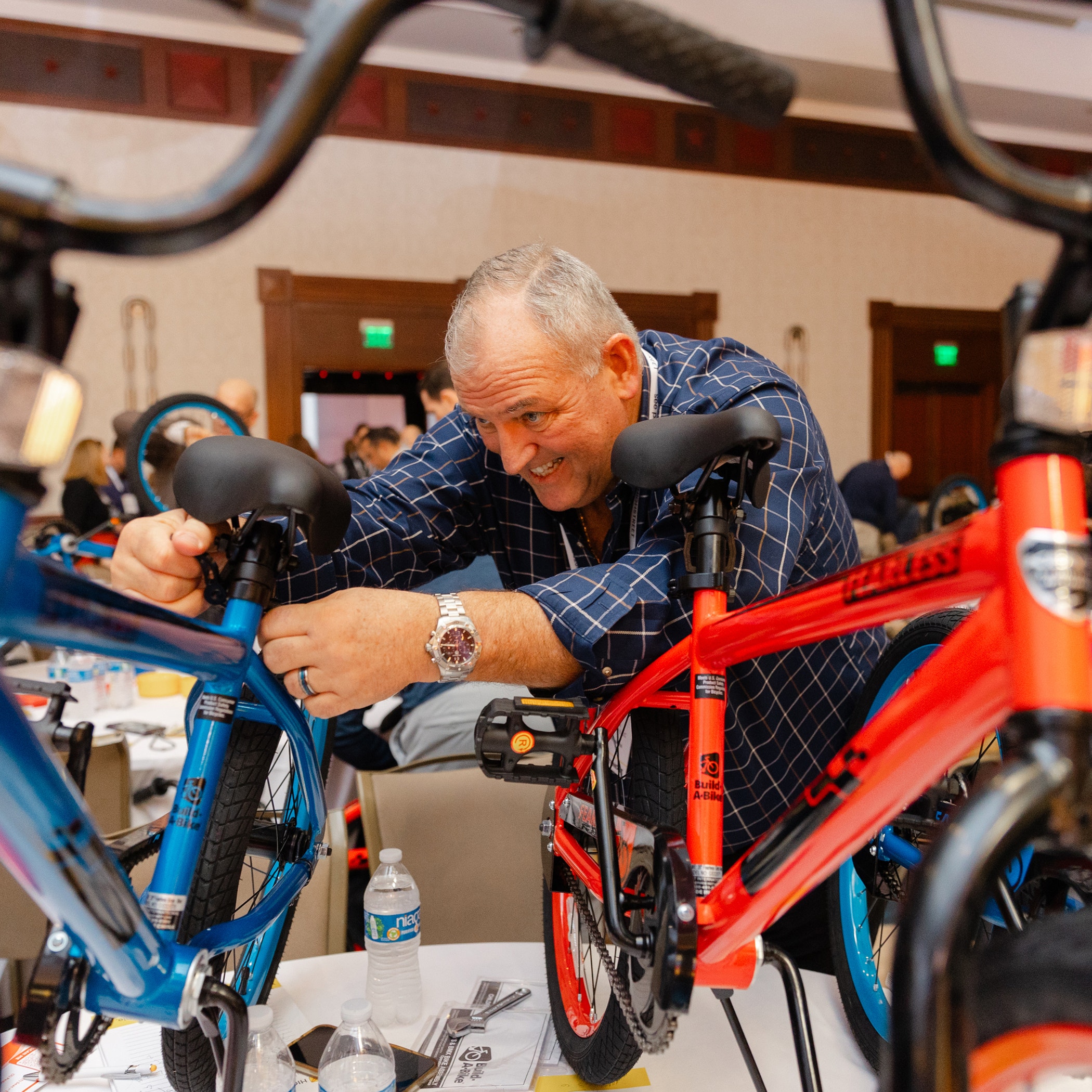 Man assembling small bicycles during an indoor team-building activity.