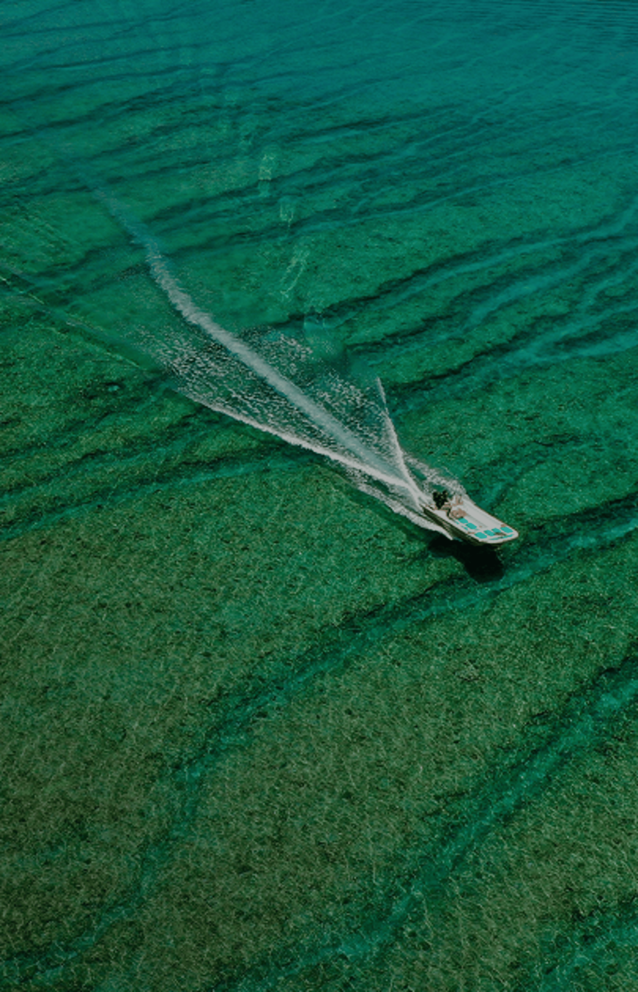 Aerial view of beautiful turquoise ocean with waves and a boat.