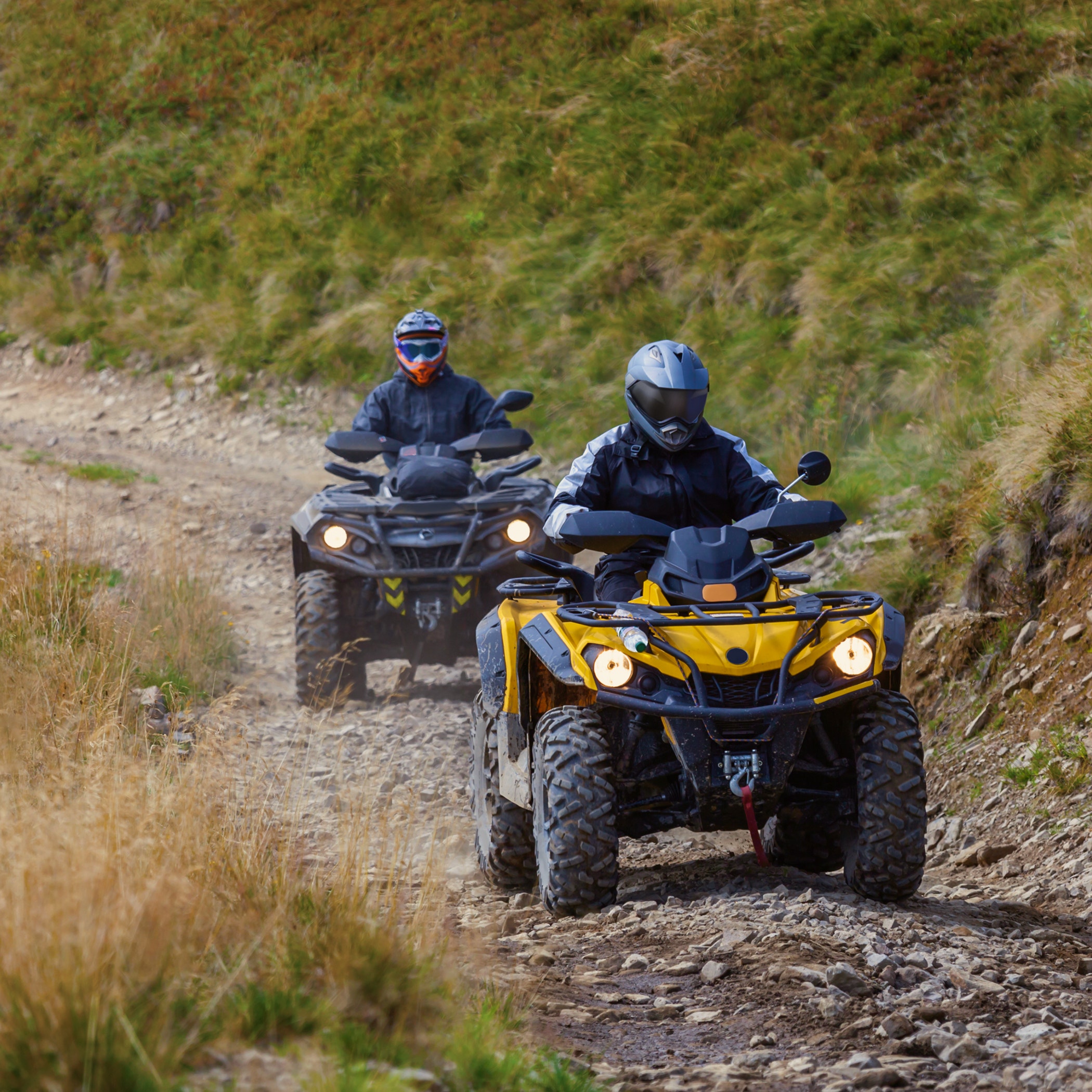Front view of quad bikes zipping along a country road.