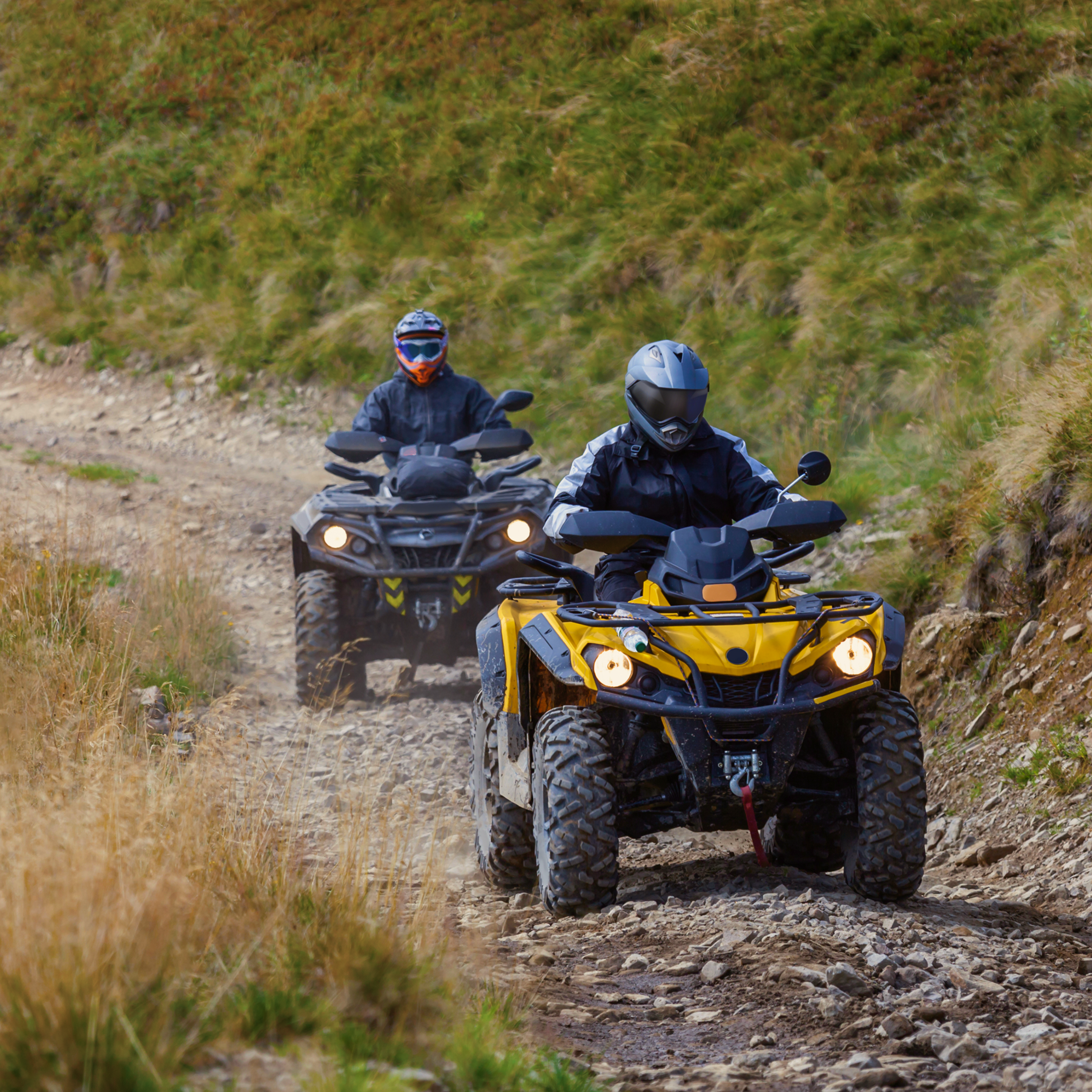Front view of quad bikes zipping along a country road.