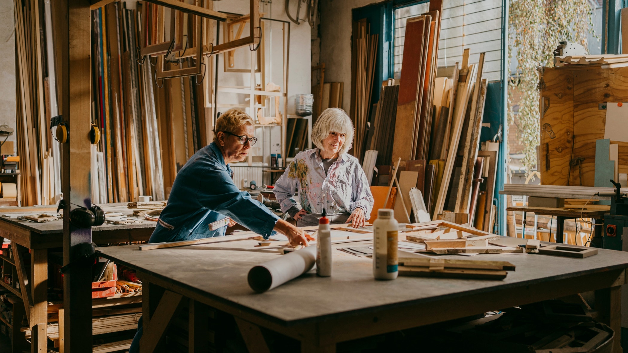 Senior female carpenter assisting colleague while working at repair shop.