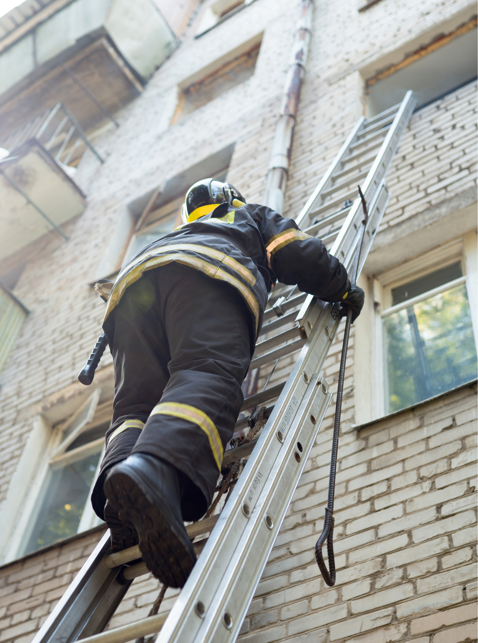Fireman climbs stairs up in burning brick house.
