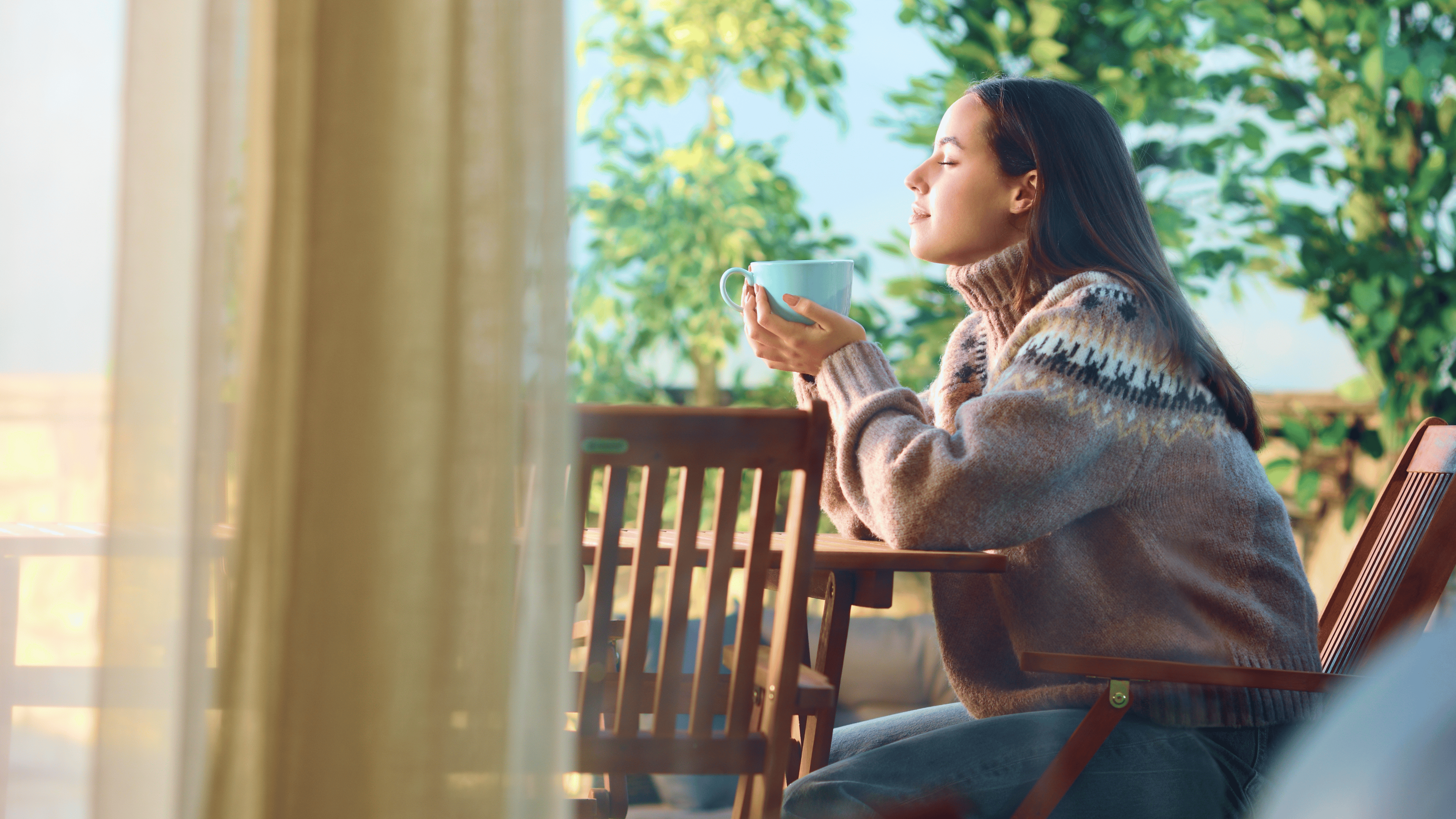 Side view portrait of a woman sitting in a terrace relaxing and drinking coffee at home.