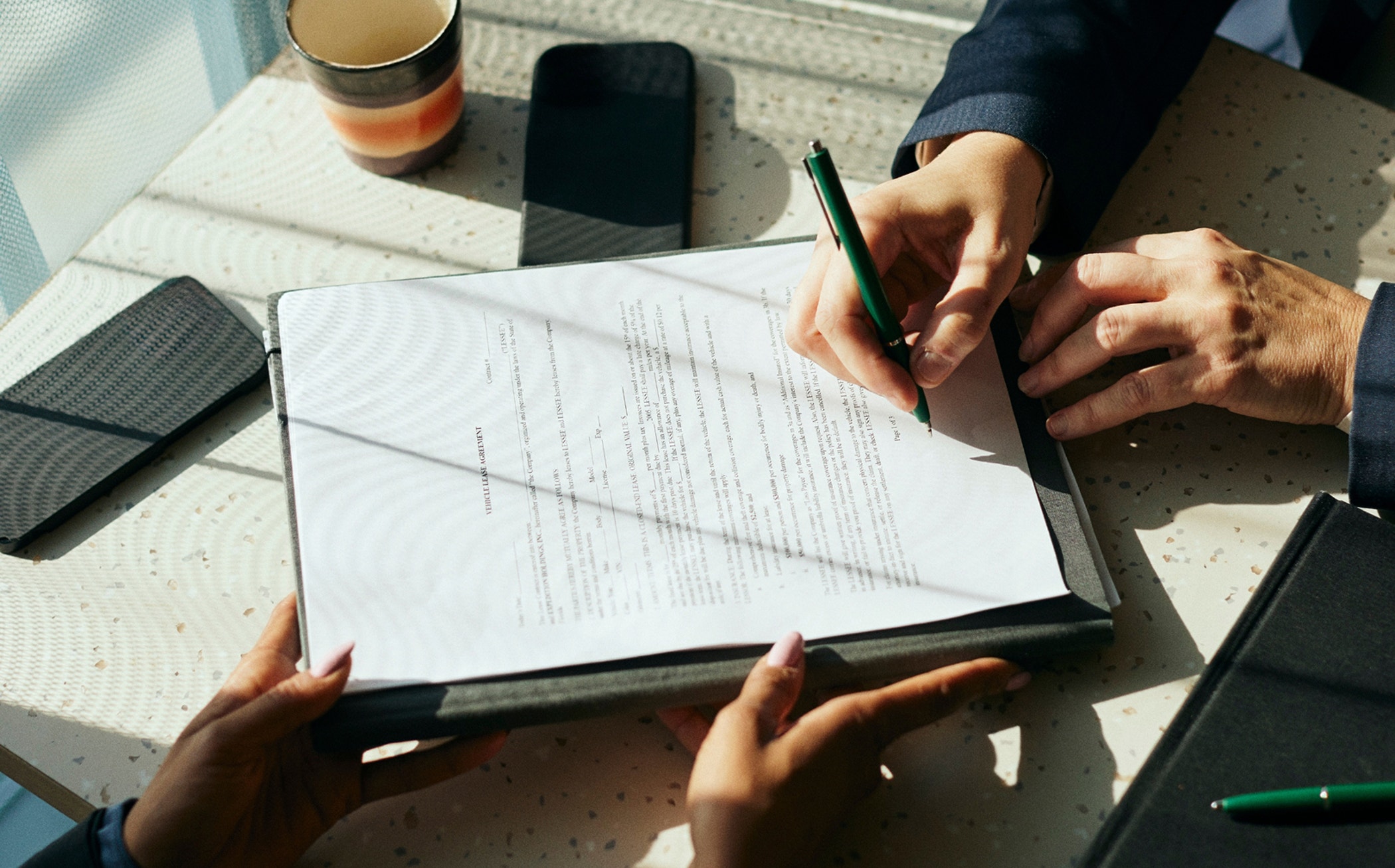 High angle view of female client signing contract with businesswoman in office.