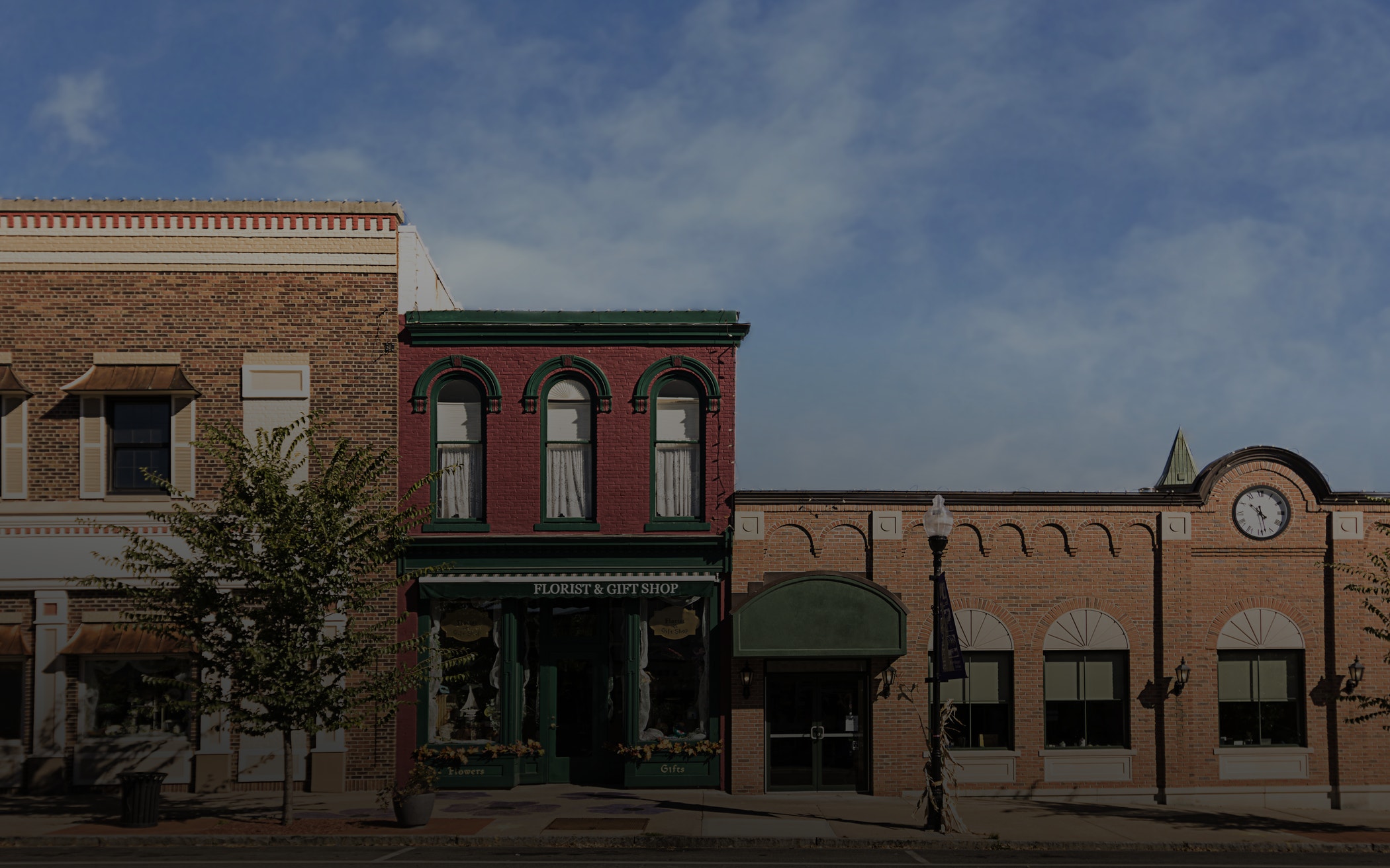 A photo of a typical small town main street in the United States of America. Features old brick buildings with specialty shops and restaurants. Decorated with autumn decor.