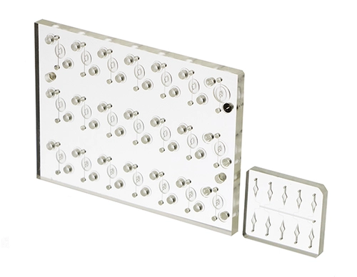 Clear COP plastic manifold with metal pegs on a white background. The large manifold has multiple rows of bulb shapes; the small one has six leaf shapes.