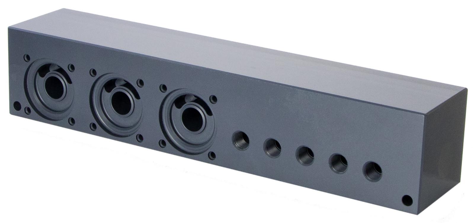 A rectangular dark gray plastic manifold with several circular openings and threaded holes, used in hydraulic or pneumatic systems.