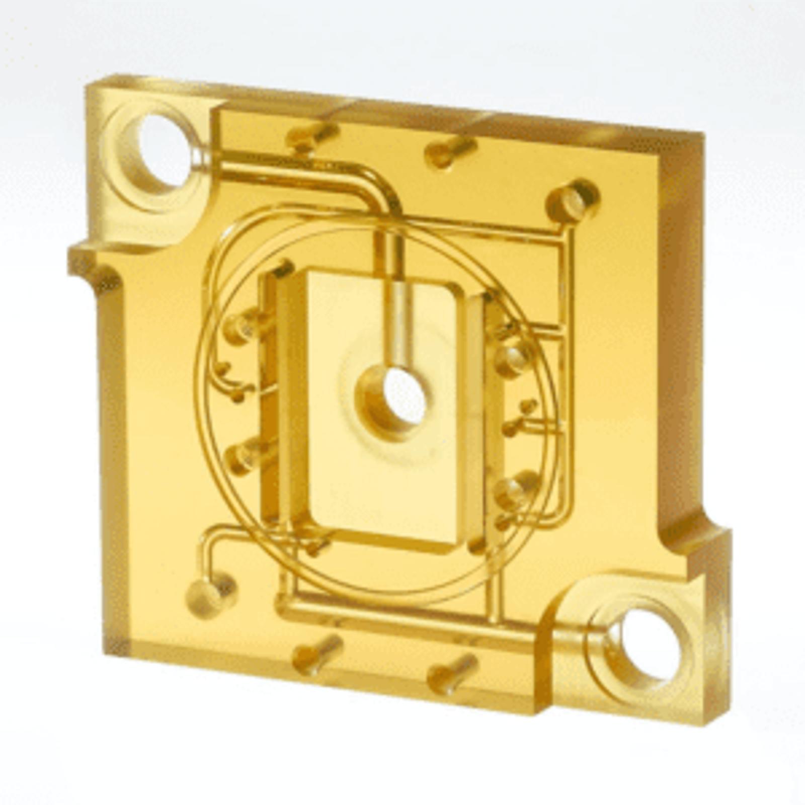Transparent amber-colored rectangular ULTEM plastic component with internal channels and holes featuring two large corner holes and intricate internal pathways as a custom microfluidic component
