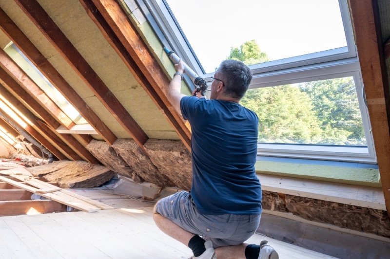 man caulking a window in his house