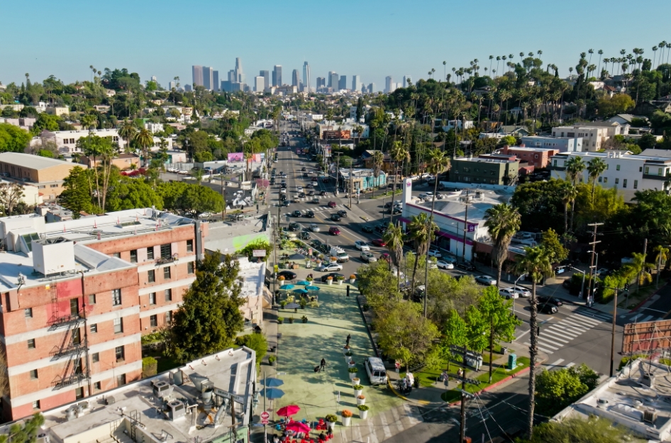 Aerial view of the dense urban downtown district in Los Angeles — one of the top cities people are moving out of — featuring city streets lined with palm trees on a sunny day.