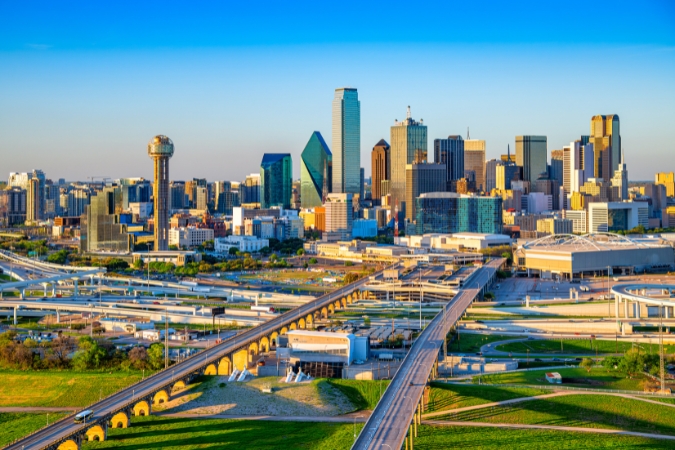 A view of the Dallas skyline, with skyscrapers and multiple interstate roads, highlighting one of the popular cities people are moving to in 2026.
