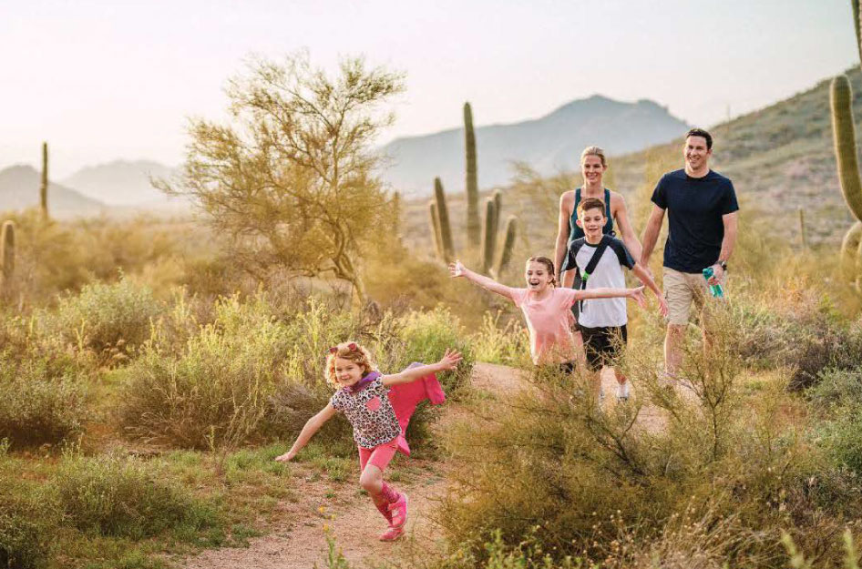 A young family is hiking through the Sonoran Desert near Scottsdale, Arizona, on a sunny day.