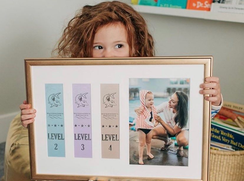 A little girl is holding up a memento from her swimming lessons.