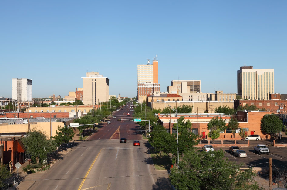 Aerial view of Downtown Lubbock, Texas, on a sunny day, featuring a few tall buildings among many shorter warehouse-style structures.