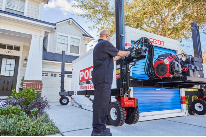 A PODS driver is using PODZILLA to position a PODS container in a residential driveway.