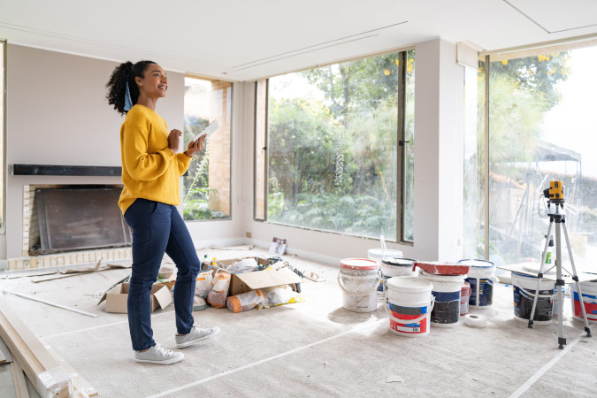 A young woman is standing in her living room, which she is in the middle of renovating.
