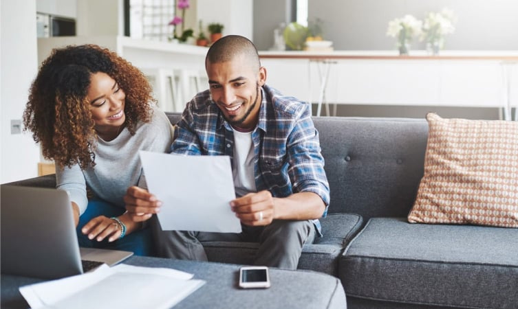 A happy couple is reviewing their finances together in their living room.