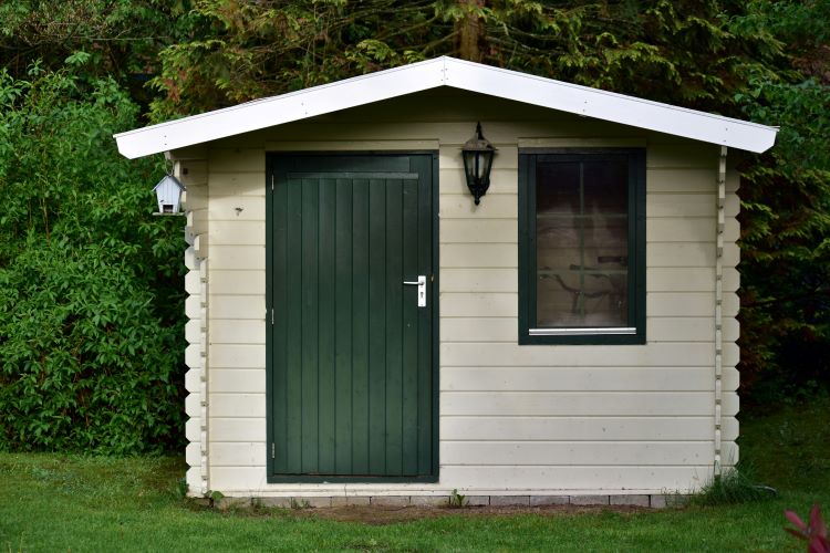 A small outdoor storage shed with a green door, perfect for outdoor storage organization.