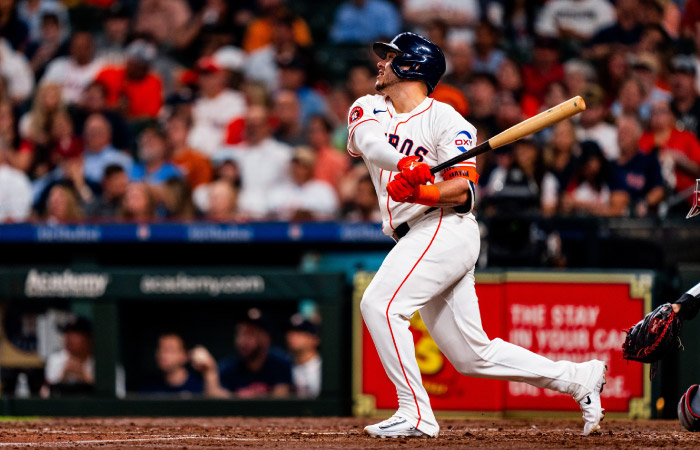 A Houston Astros batter is watching the ball after making a hit during a professional baseball game.