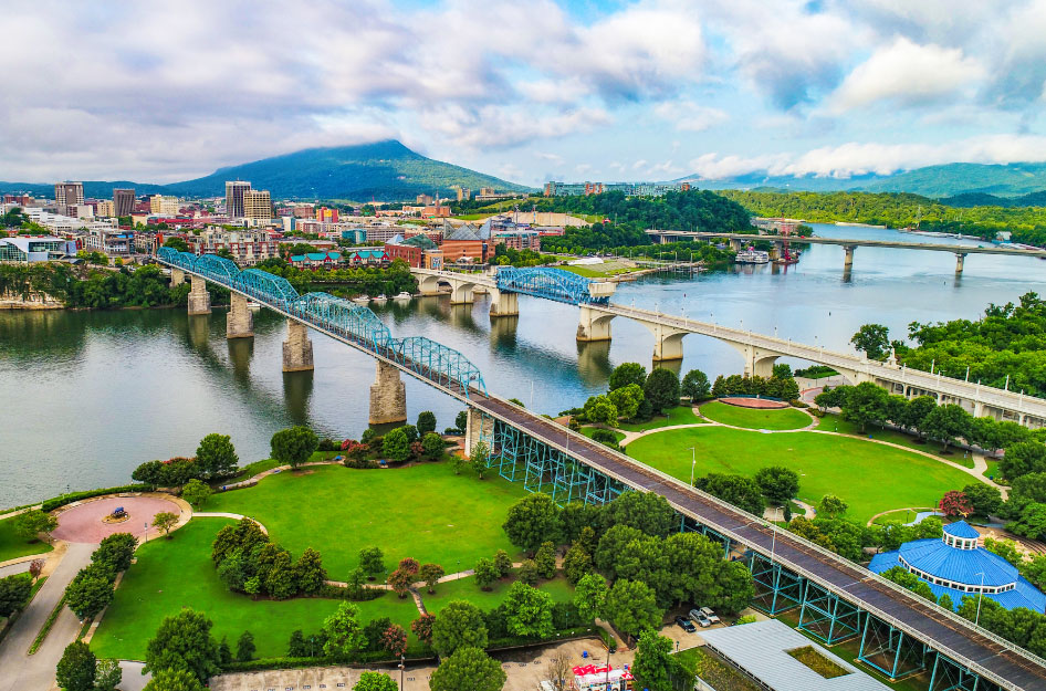 Aerial view of Chattanooga, Tennessee, on a vibrant summer day. The river looks calm, the mountain is clear, and the green spaces of the city are shining with life.