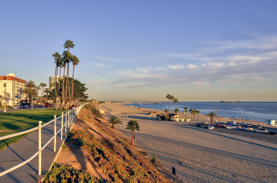 View of a beach parking lot, condos, and a seaside park in Long Beach, California.