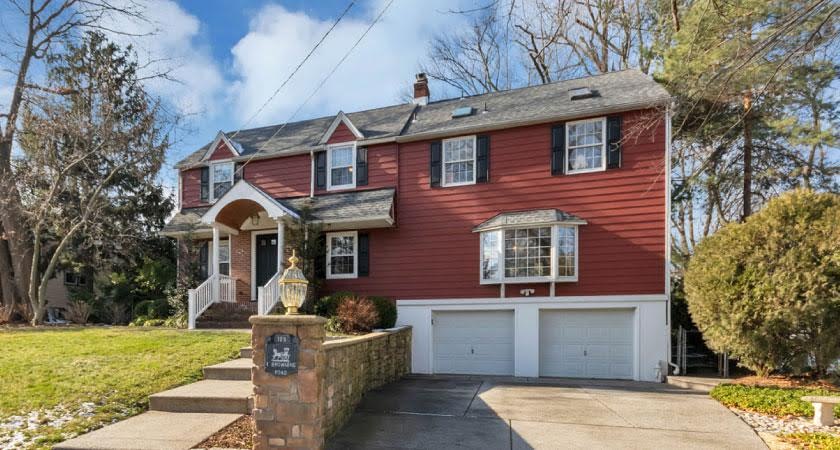 A red, two-story colonial home in Collingswood, New Jersey — a city close to Philadelphia — featuring a two-car garage with a bay window above it.