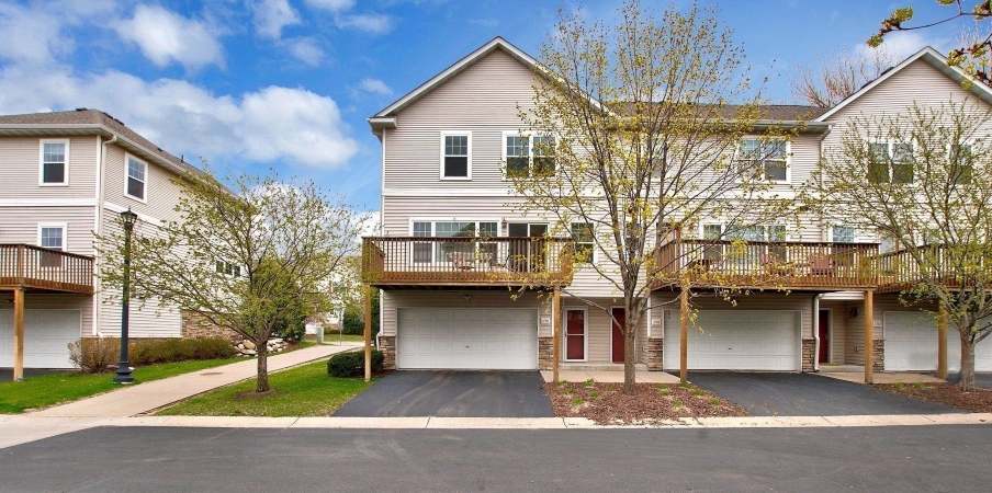View of a few townhomes in a neighborhood in Northeast Minneapolis. Each home features three stories with a two-car garage on the ground floor and a large wooden deck above the garage.