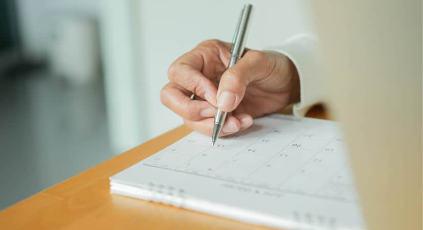 Someone using a calendar to plan the best time for a garage sale