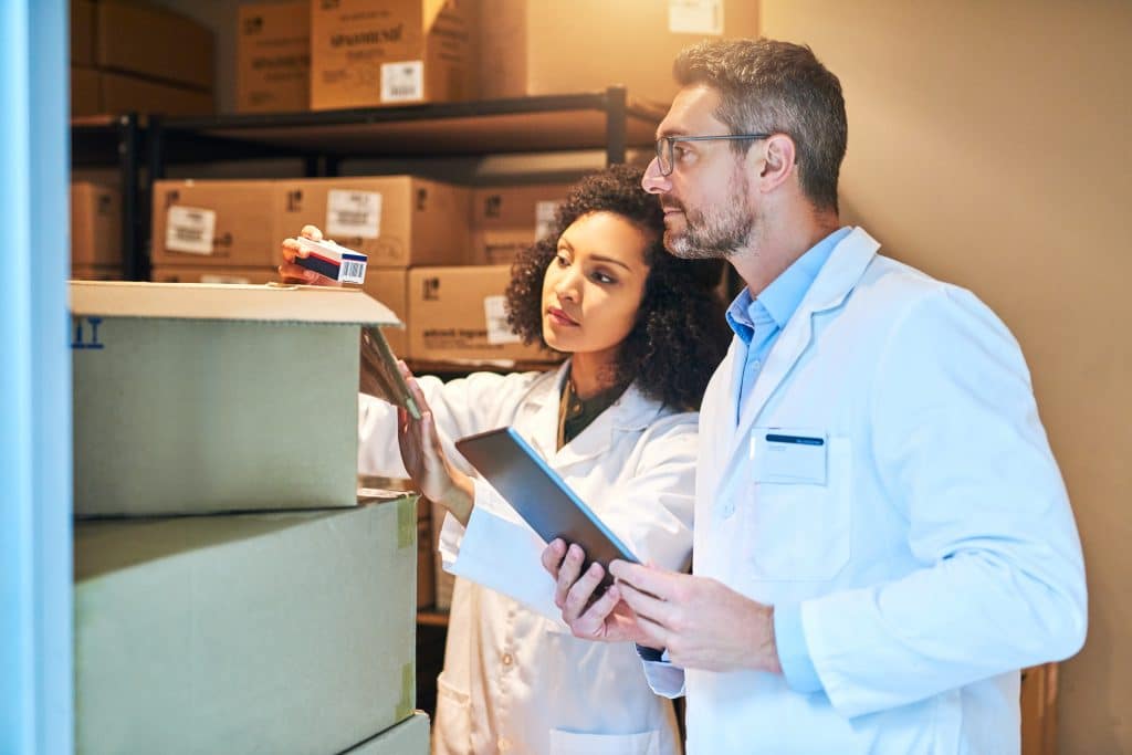 Two medical hospital supply chain professionals looking at boxes in a warehouse