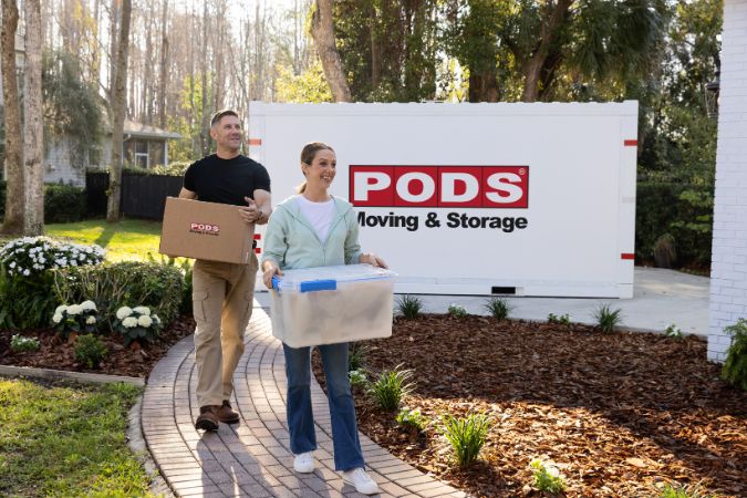 A couple is unpacking boxes from a PODS portable moving container after moving to a different climate.