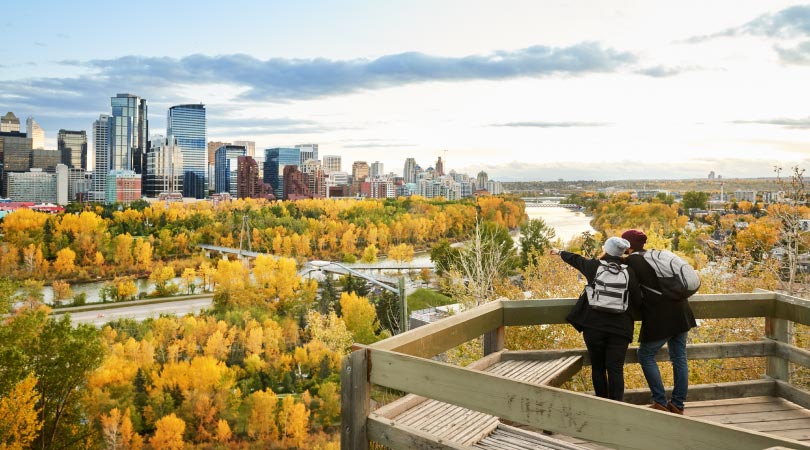 Two people looking out at Downtown Calgary and the city’s colourful landscape as the leaves change in the fall.