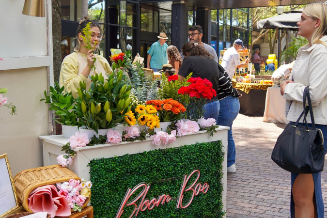 A young woman is assembling a fresh bouquet of flowers at a sidewalk flower stand in Tampa — one of the best cities to live in Florida.