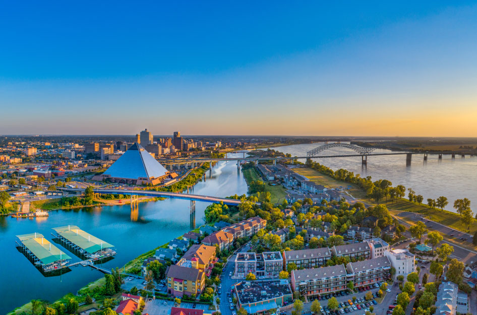 Aerial view of Memphis, TN, featuring the Mississippi River, multiple bridges, and the Memphis Pyramid.