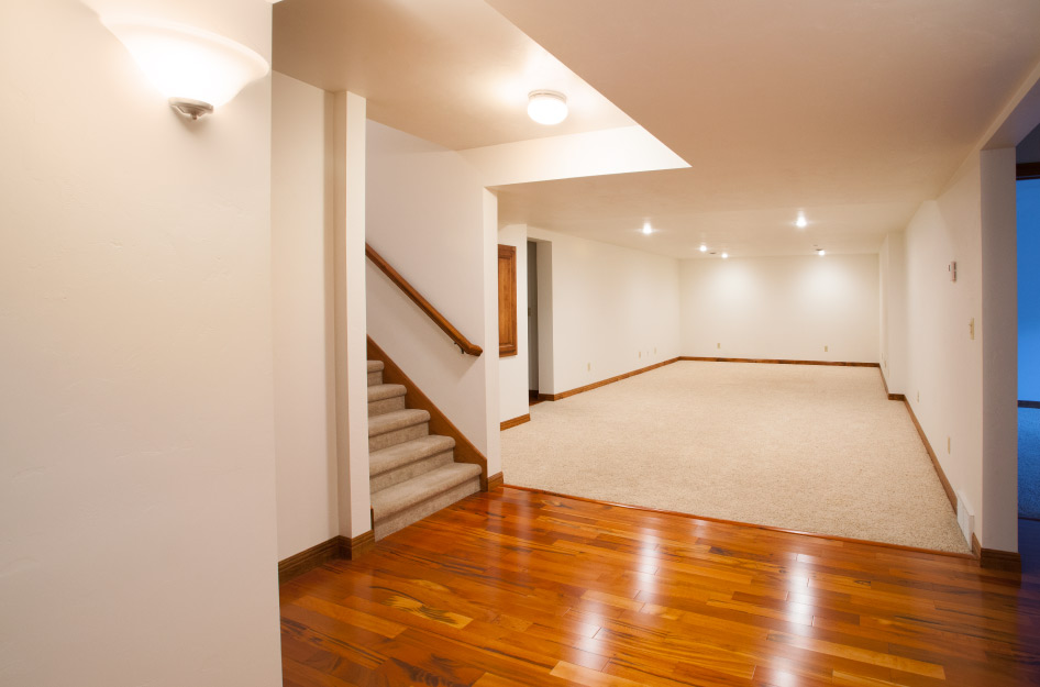 View of a finished basement with carpeted stairs, white walls, and a mix of carpeted and hardwood flooring.