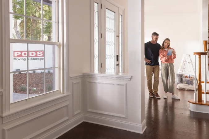 A couple is comparing paint swatches in their new home after moving to a more affordable area, one of the top reasons Americans are moving.